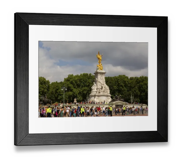 Framed Print : Crowd surrounds Victoria Memorial's golden statue amidst overcast skies and green trees in the City of Westminster
