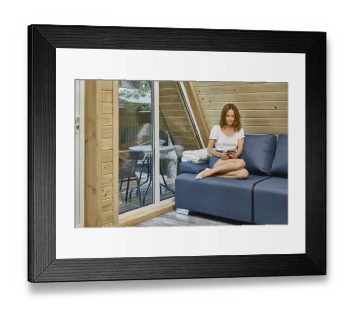 Framed Print : Cheerful woman sits comfortably on a sofa in tiny house