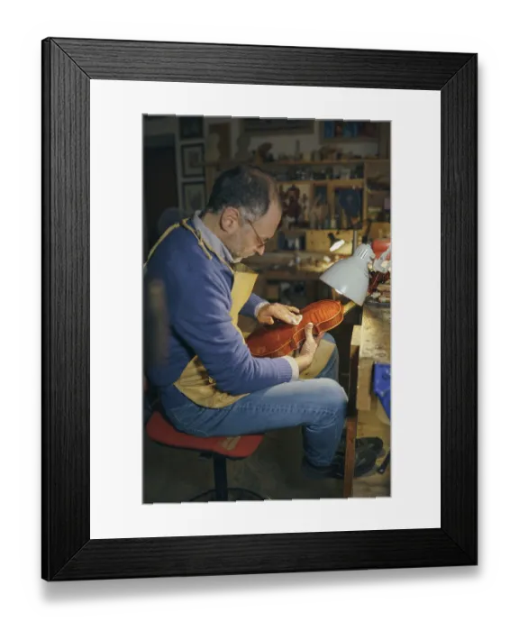 Framed Print : Violin maker carefully crafting a new instrument in his workshop surrounded by various tools showcasing his skills