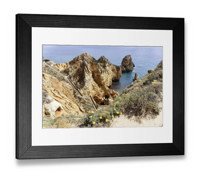 Framed Print : Jagged rocks on the coast of the Algarve with a path along the cliffs
