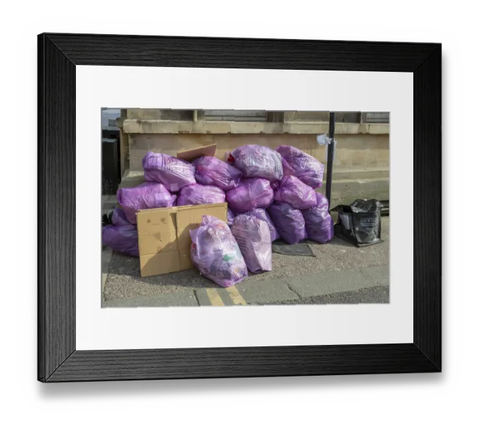 Framed Print : Council bags of rubbish waste piled on street corner