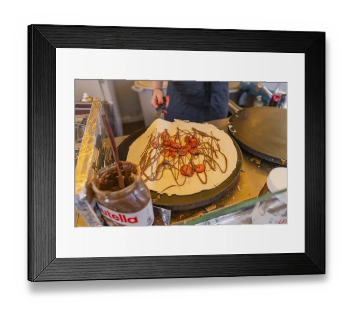 Framed Print : Preparation of a crepe with Nutella and strawberries in a lively kitchen