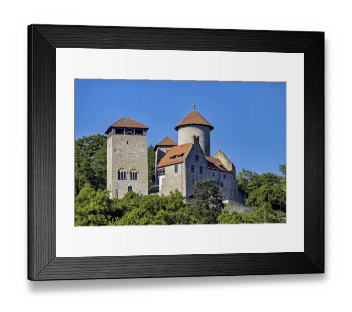 Framed Print : A medieval castle with two towers against a clear blue sky and surrounded by green trees Framed Print : A medieval castle with two towers against a clear blue sky and surrounded by green trees