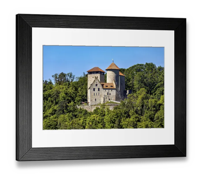 Framed Print : A medieval castle with two towers on a wooded hill under a blue sky