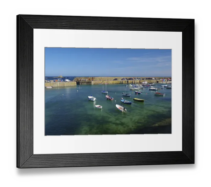 Framed Print : Harbour with small boats on calm water under a clear blue sky