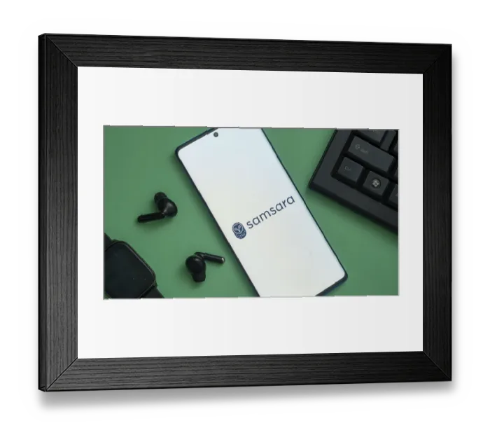Framed Print : Samsara logo displayed on a smartphone with earbuds and keyboard nearby