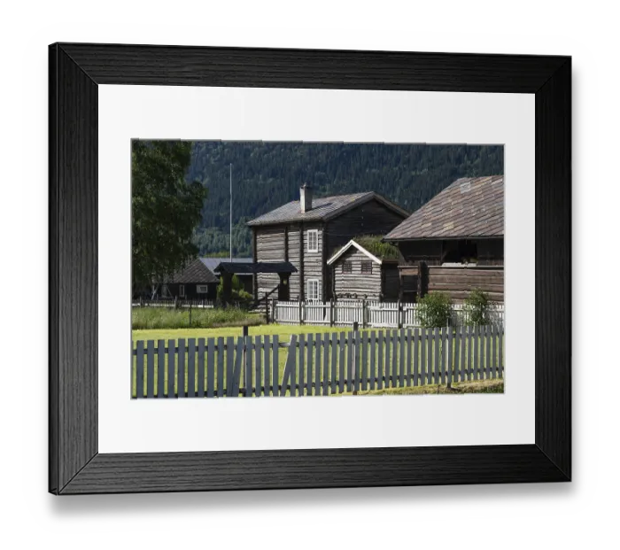 Framed Print : Wooden houses covered with slate tiles behind wooden fences in front of a wooded mountain landscape Framed Print : Wooden houses covered with slate tiles behind wooden fences in front of a wooded mountain landscape