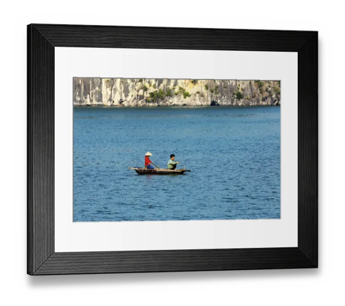 Framed Print : Two people in a small boat in front of a rocky coast with deep blue water Framed Print : Two people in a small boat in front of a rocky coast with deep blue water
