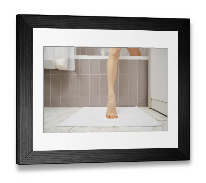 Framed Print : A person is stepping out of a bathtub onto a soft white mat Framed Print : A person is stepping out of a bathtub onto a soft white mat