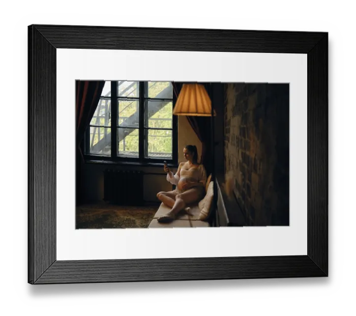Framed Print : A pregnant woman sits comfortably on a couch at home