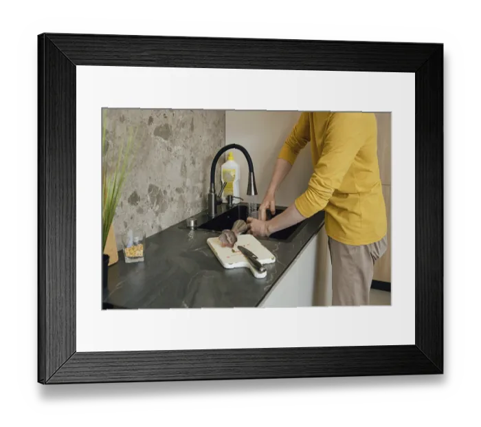 Framed Print : A person wearing a yellow shirt is washing utensils and a cutting board in a dark kitchen sink Framed Print : A person wearing a yellow shirt is washing utensils and a cutting board in a dark kitchen sink