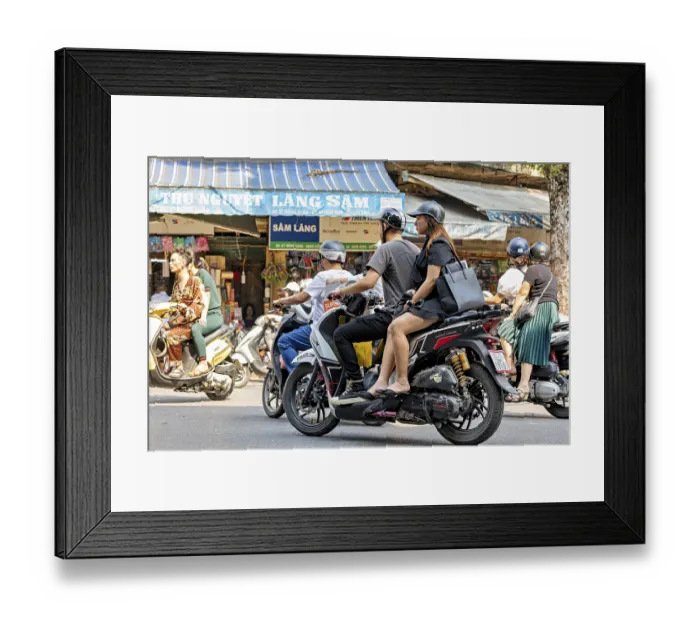 Framed Print : People ride scooters through a busy city shopping street during the day