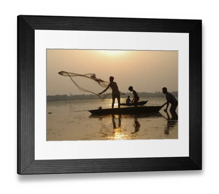 Framed Print : Fishermen in boat throwing net in silhouette