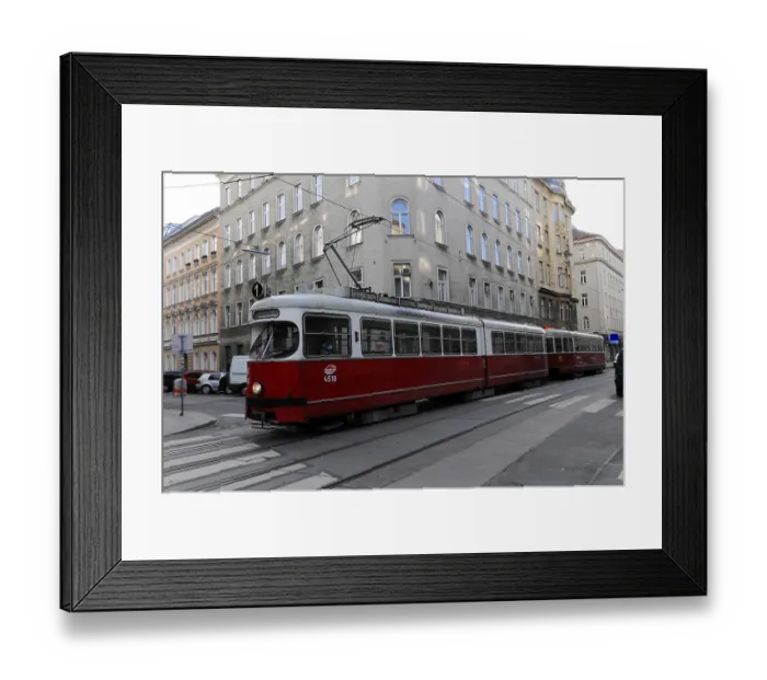 Framed Print : Red tram travelling through an urban environment with historic buildings