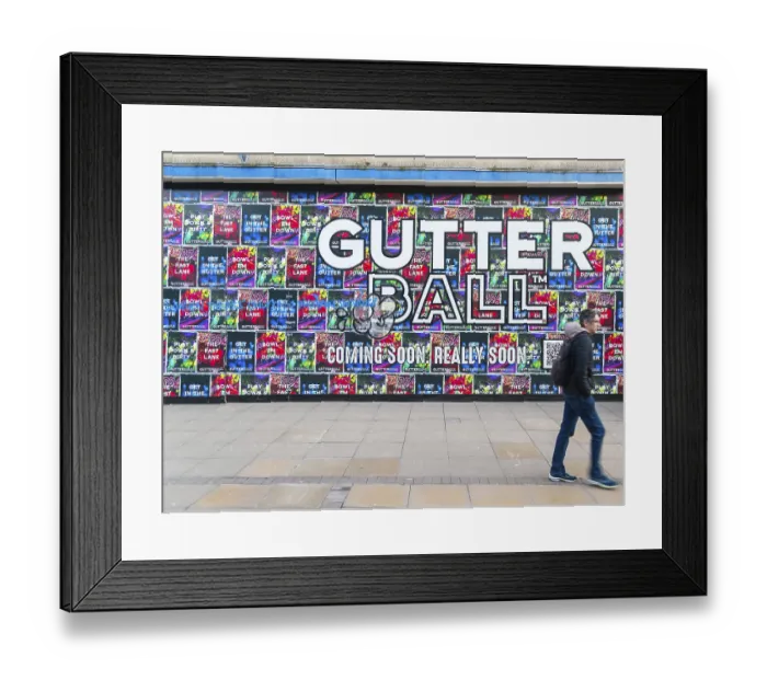 Framed Print : Person waking past posters on shopfront advertising Gutter Ball ten pin bowling attraction