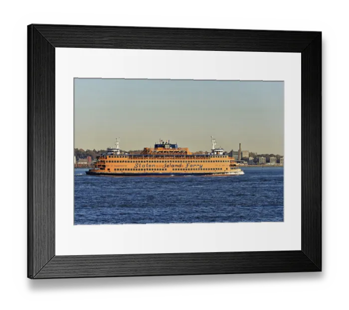 Framed Print : Orange-coloured Staten Island Ferry on water against a city backdrop