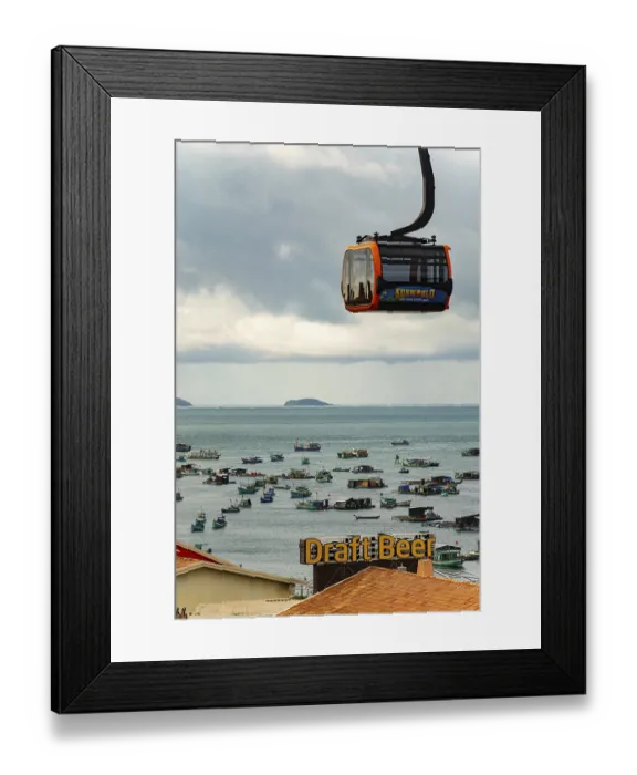 Framed Print : Close-up of a cable car over the sea with islands in the background under a cloudy sky Framed Print : Close-up of a cable car over the sea with islands in the background under a cloudy sky