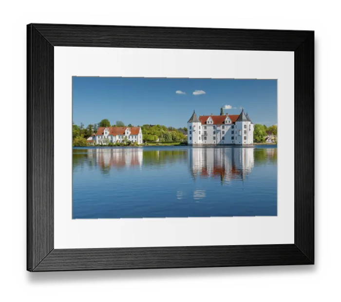 Framed Print : Glucksburg moated castle under a blue sky with white clouds