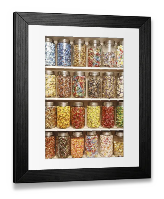 Framed Print : Chocolates kept in different glass jars on selves in shop