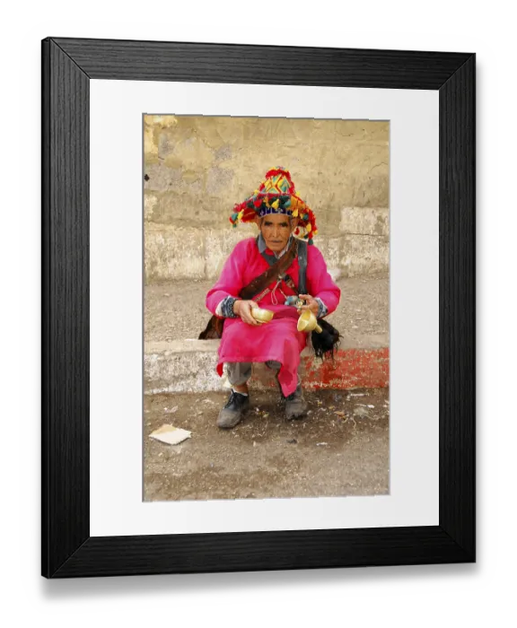 Framed Print : Water vendor, Elderly man in traditional clothes with colourful hat holding bowls and sitting by the road