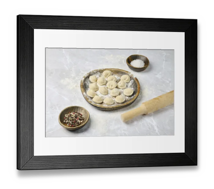 Framed Print : A wooden plate holds freshly made dumplings surrounded by bowls of spices and salt on a flour-dusted countertop