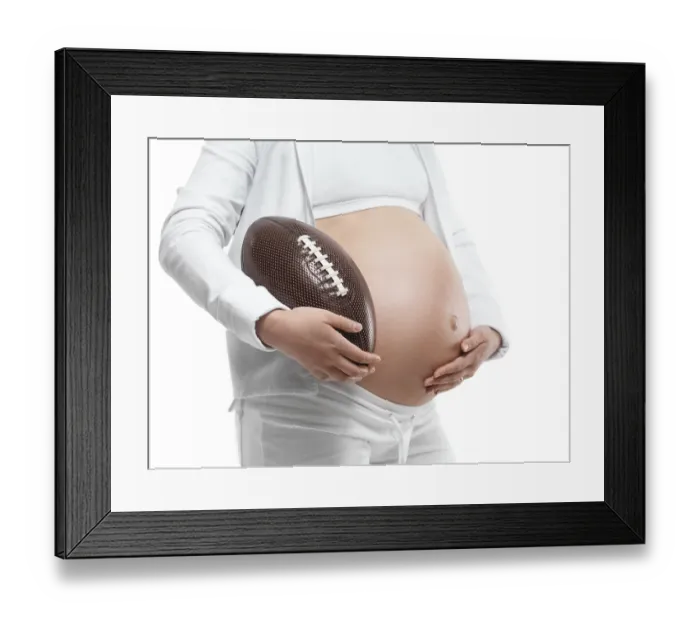 Framed Print : Pregnant young woman holding a football under her arm
