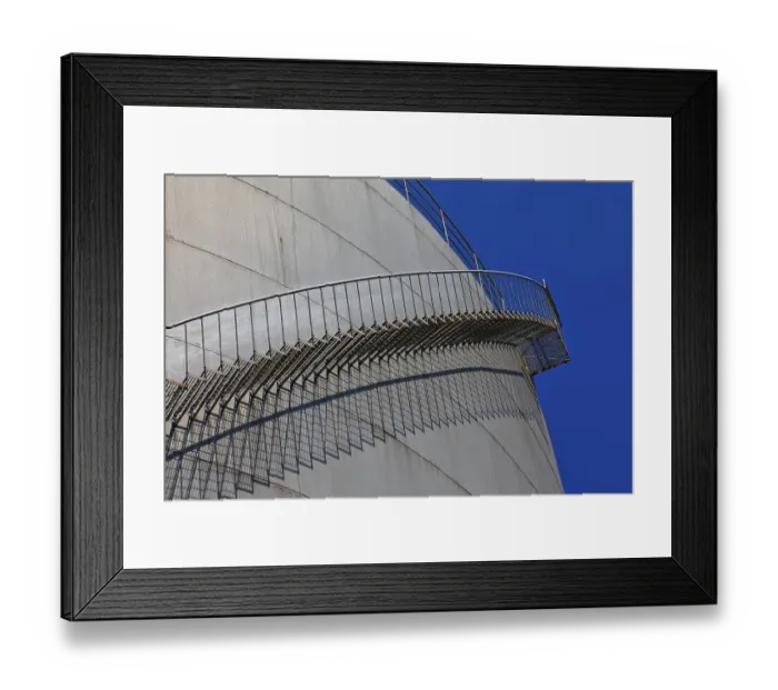 Framed Print : Metal staircase winds around a large tank in an industrial environment