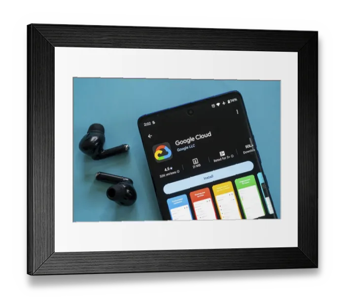 Framed Print : Smartphone displaying Google Cloud app with black earbuds against blue background