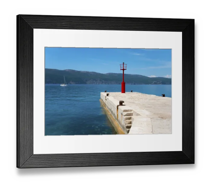 Framed Print : Sailing boat next to a stony jetty with a red lighthouse under a clear blue sky Framed Print : Sailing boat next to a stony jetty with a red lighthouse under a clear blue sky