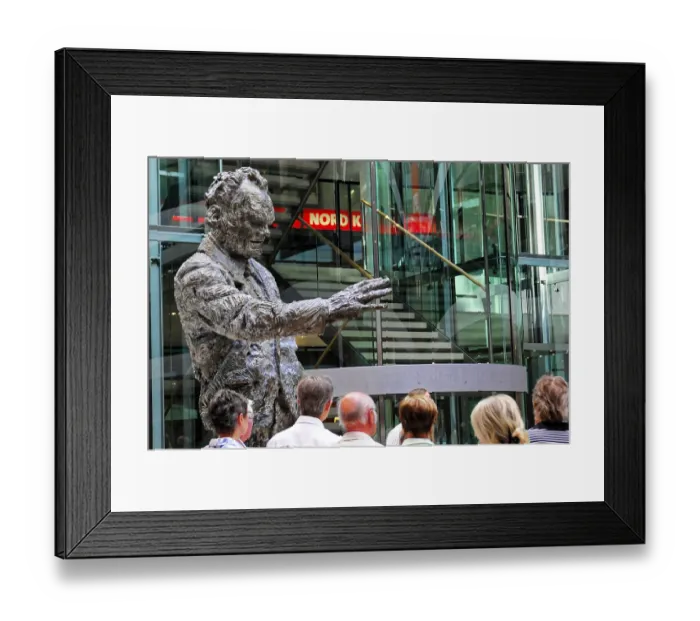 Framed Print : A bronze sculpture of a man stands in a modern building at an exhibition