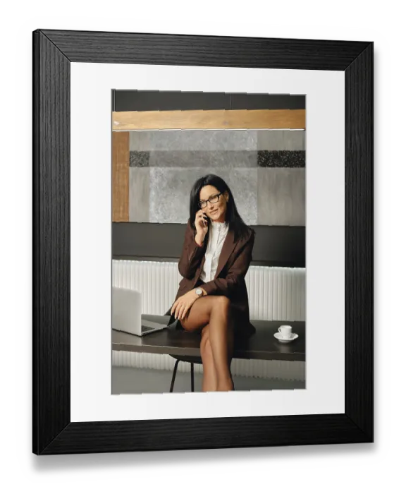 Framed Print : Positive businesswoman engages in a phone conversation while seated at a table