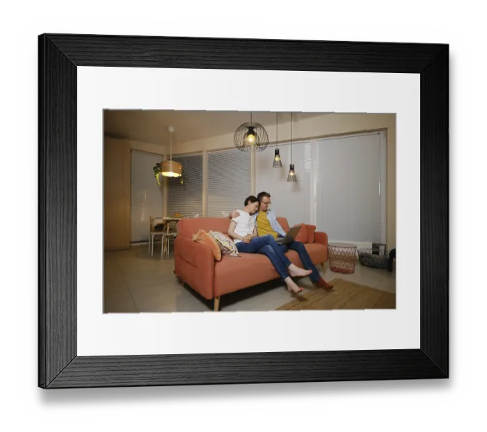 Framed Print : A husband embraces his wife while sitting on a couch in a modern living room Framed Print : A husband embraces his wife while sitting on a couch in a modern living room
