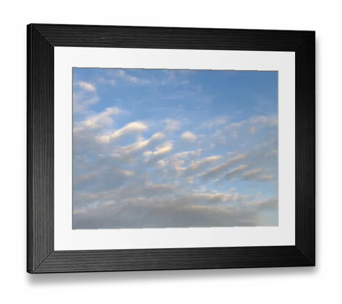 Framed Print : Diagonally arranged stratocumulus clouds are illuminated by warm sunlight at dusk