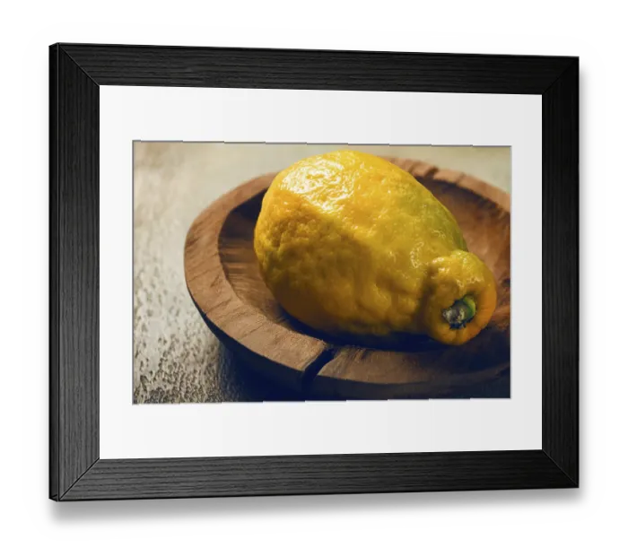 Framed Print : A vibrant lemon sits on a rustic wooden plate