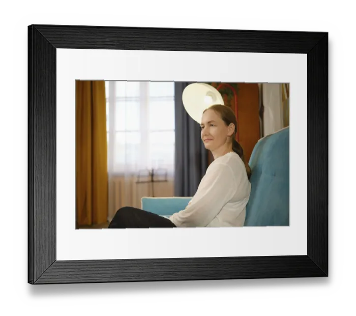 Framed Print : A woman in a white top sits comfortably on a blue couch Framed Print : A woman in a white top sits comfortably on a blue couch