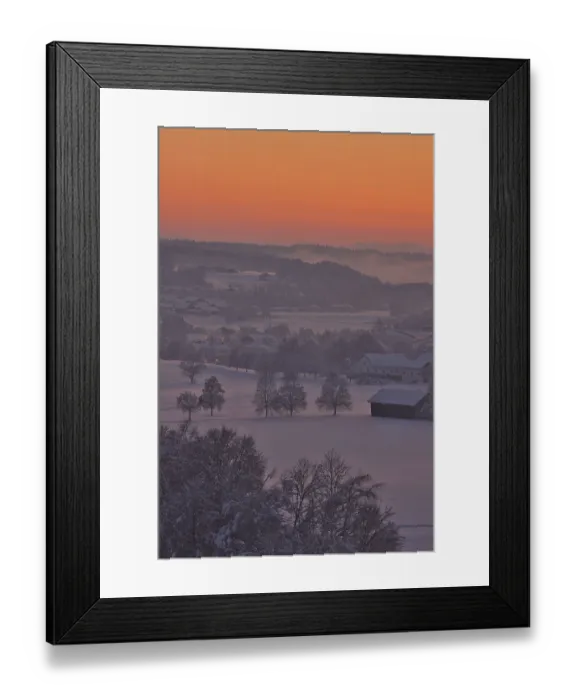 Framed Print : Snowy winter landscape with trees and houses in the sunset