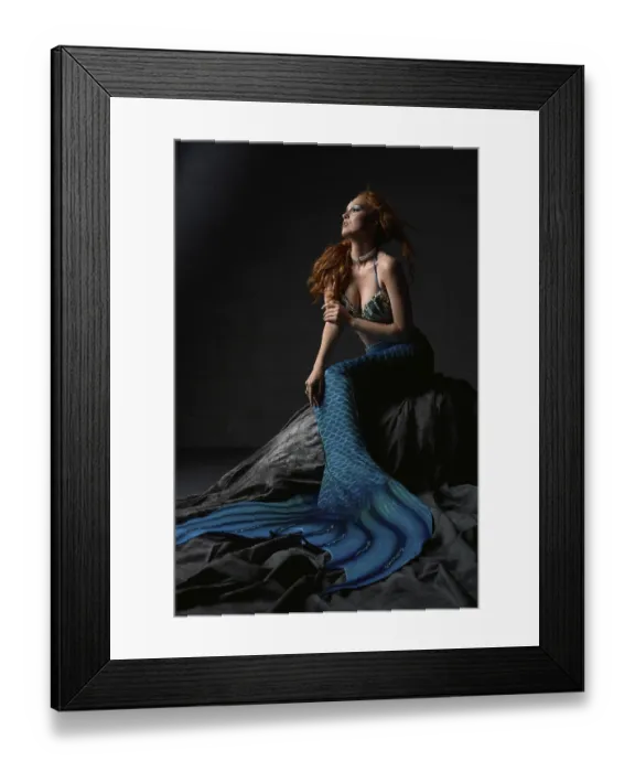 Framed Print : Full length of young redhead female wearing bra and blue mermaid tail sitting on rock against black background Framed Print : Full length of young redhead female wearing bra and blue mermaid tail sitting on rock against black background