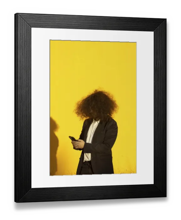 Framed Print : Vertical portrait of unrecognizable long-haired businessman with cellphone over yellow background