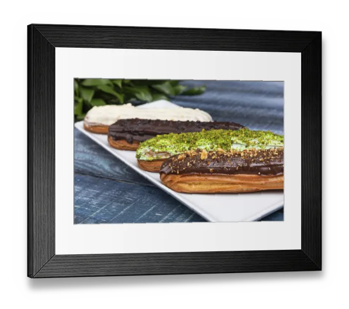 Framed Print : Tasty chocolate eclair cakes with leaves on the blue background