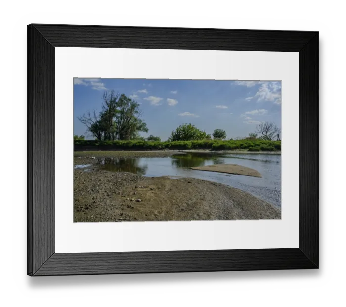 Framed Print : A river with a sandbank and surrounded by trees under a blue sky