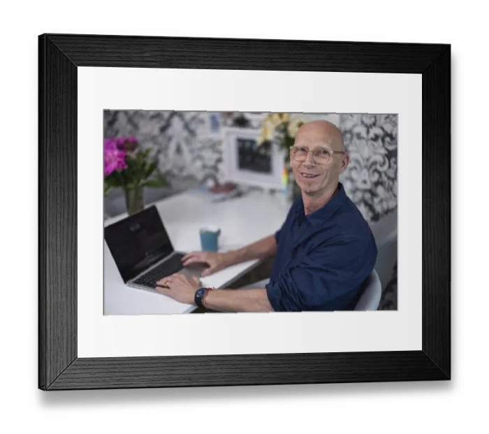 Framed Print : Elderly, bald man with a friendly smile sitting in his living room at a table with flowers and a cup of coffee Framed Print : Elderly, bald man with a friendly smile sitting in his living room at a table with flowers and a cup of coffee