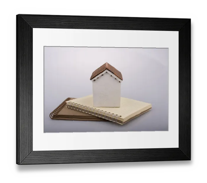 Framed Print : Little model house placed on an a brown color notebook