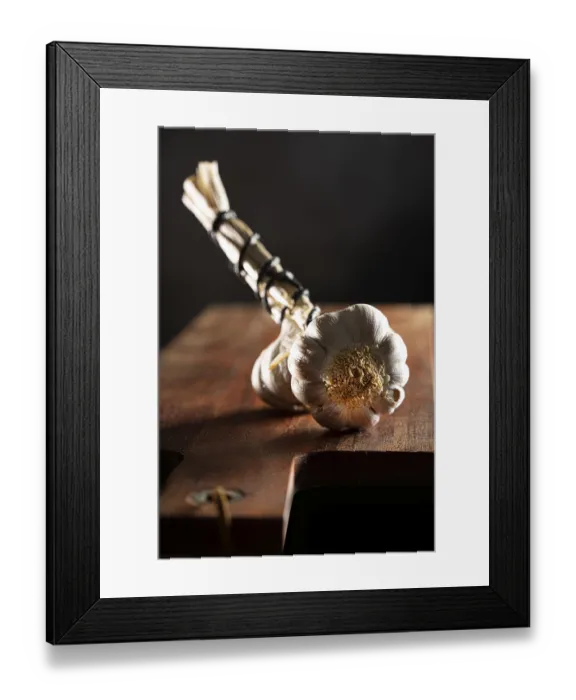 Framed Print : Garlic bulbs on wooden board, dark background