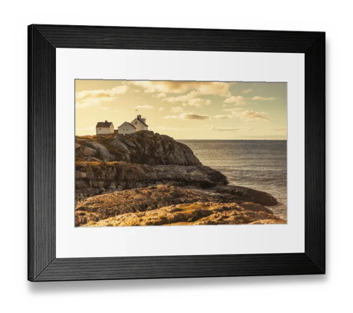 Framed Print : A lighthouse and house on rocky cliffs by the ocean at sunset Framed Print : A lighthouse and house on rocky cliffs by the ocean at sunset