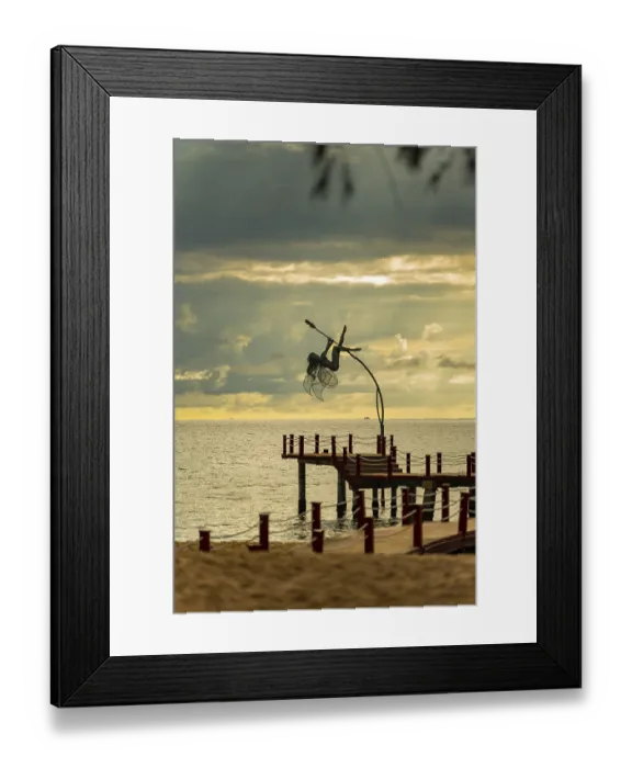 Framed Print : Dynamic sculpture of an acrobat on a pier against an ocean sunset with dramatic clouds Framed Print : Dynamic sculpture of an acrobat on a pier against an ocean sunset with dramatic clouds