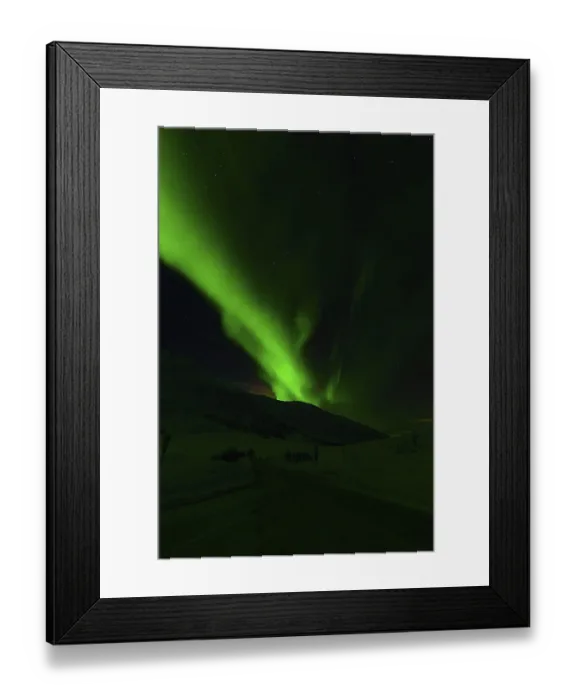 Framed Print : Green aurora borealis illuminating a dark landscape with hills and starry sky