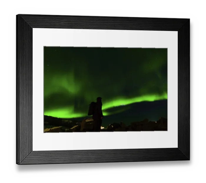 Framed Print : A lone figure silhouetted against vibrant green aurora beneath a star-lit sky