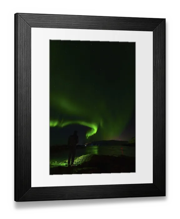 Framed Print : A silhouette by water reflecting stunning green auroras under night skies
