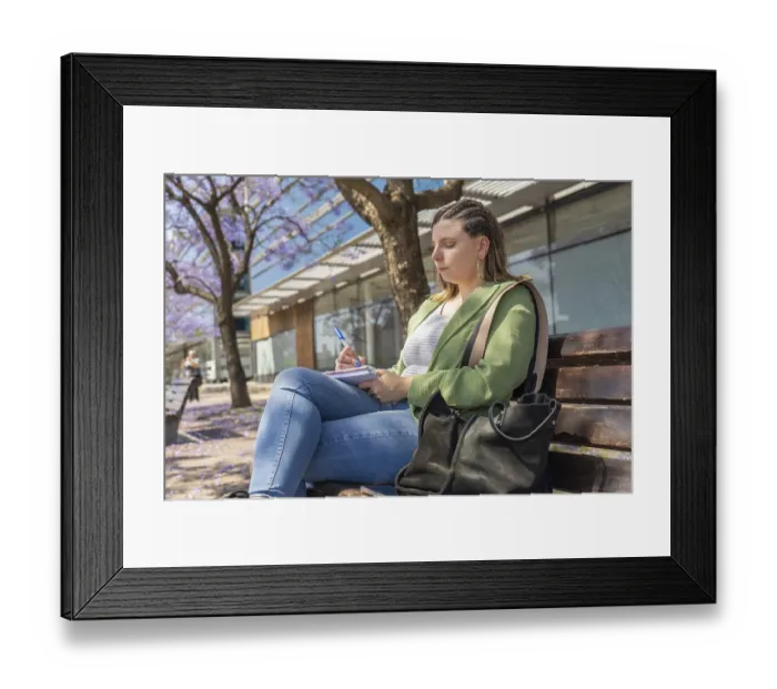 Framed Print : A young woman with braided hair sitting on a bench