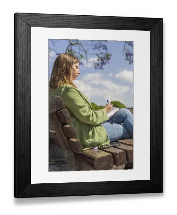 Framed Print : A vertical shot of a young woman sitting on a bench in a park Framed Print : A vertical shot of a young woman sitting on a bench in a park